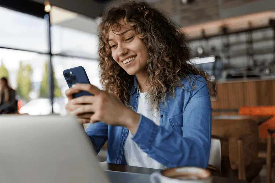 Mulher sorrindo enquanto usa o celular